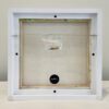 A white frame with a piece of paper in it.